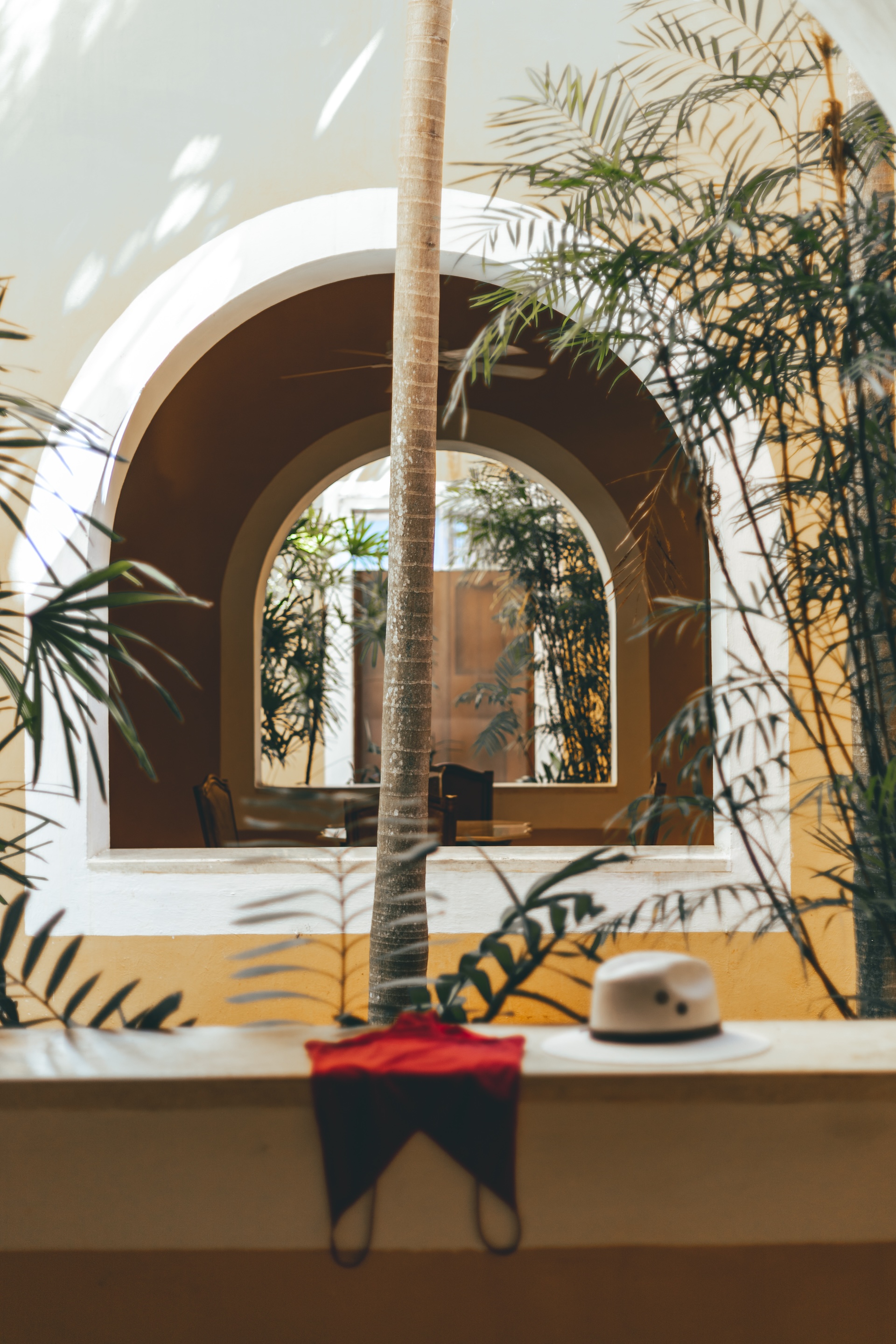 Stylishly placed hat and swimwear in the sun-dappled courtyard of Hacienda San Antonio Millet, reflecting sophisticated interior design